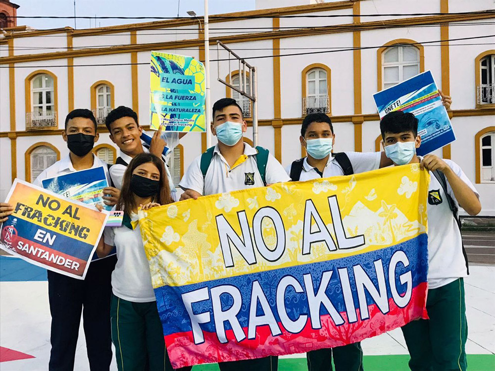 School children hold up signs and a Colombian flag on which is written 'no to fracking'.