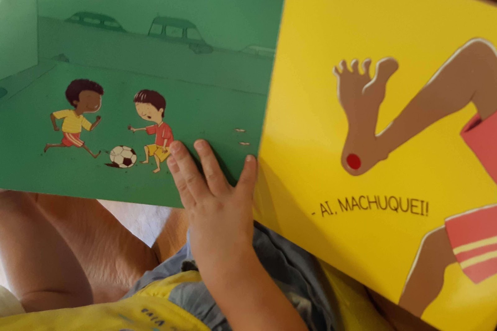 A imagem mostra uma mão de criança sobre um livro aberto.