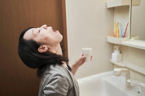 Women gargle with antivirus Woman gargle in the washroom mouthwash stock pictures, royalty-free photos & images