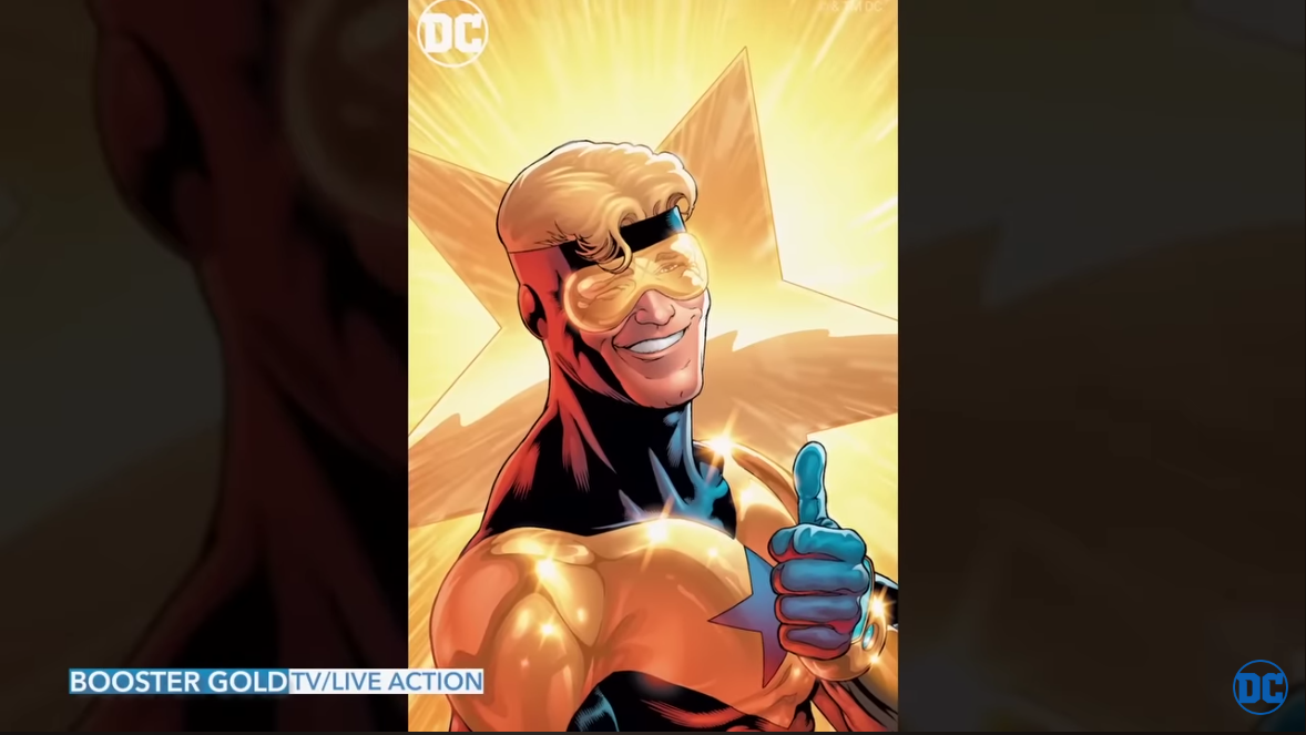 A smug looking superhero with blonde hair and wearing a gold and black suit.