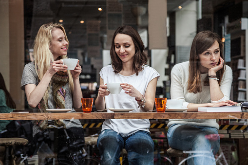 Three friends sitting at a coffee shop while two are smiling when the other one is looking away. this photo represents how depression can cause relationship issues where you feel isolated and misunderstood. Therapy for depression can help with coping skills to improve mood, functioning, and relationships. You can also get help for anxiety 
    counseling in Woodland Hills, CA 
    and with online therapy in California. 
    One woman in the group may not feel confident and worthy enough when in a group of friends. 
    91361 | 90265 | 90290 | 91367 | 91364 | 91335 