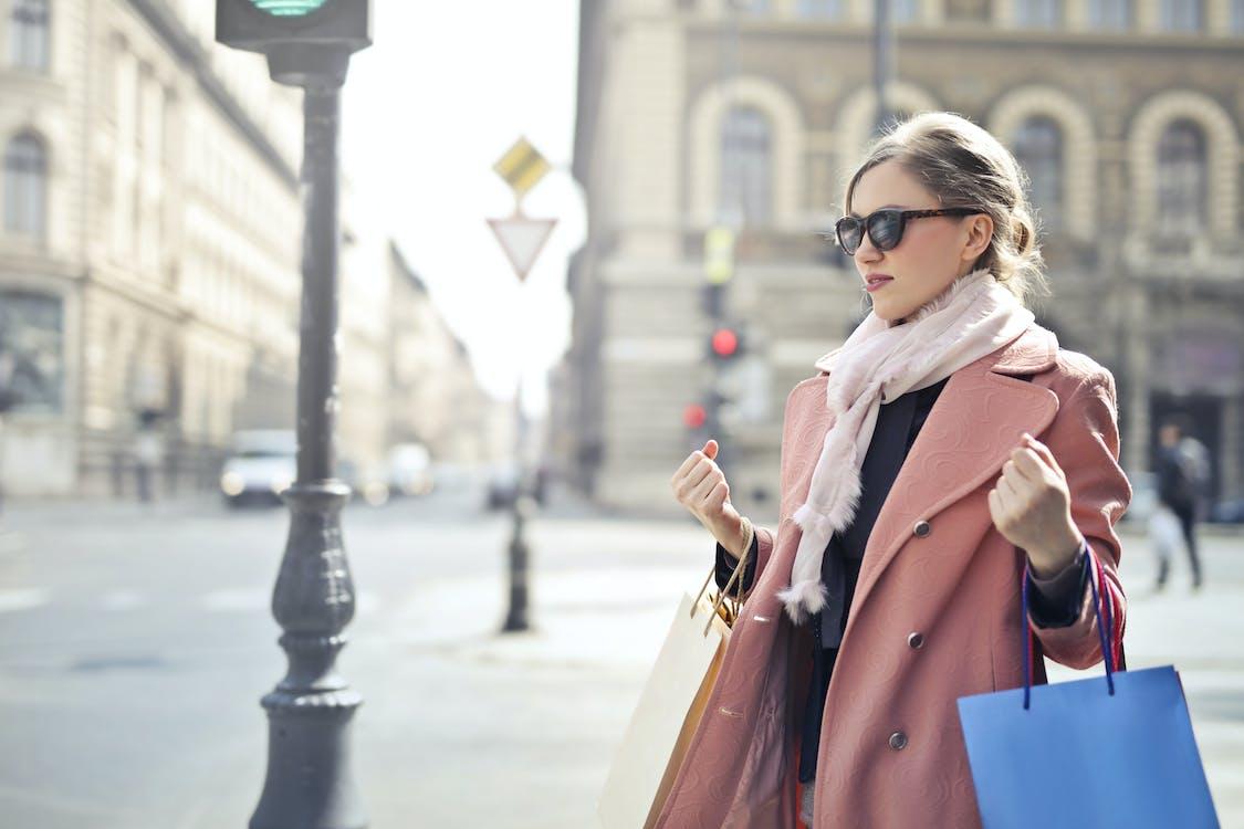 Free Woman in Pink Coat Holding Shopping Bags Stock Photo