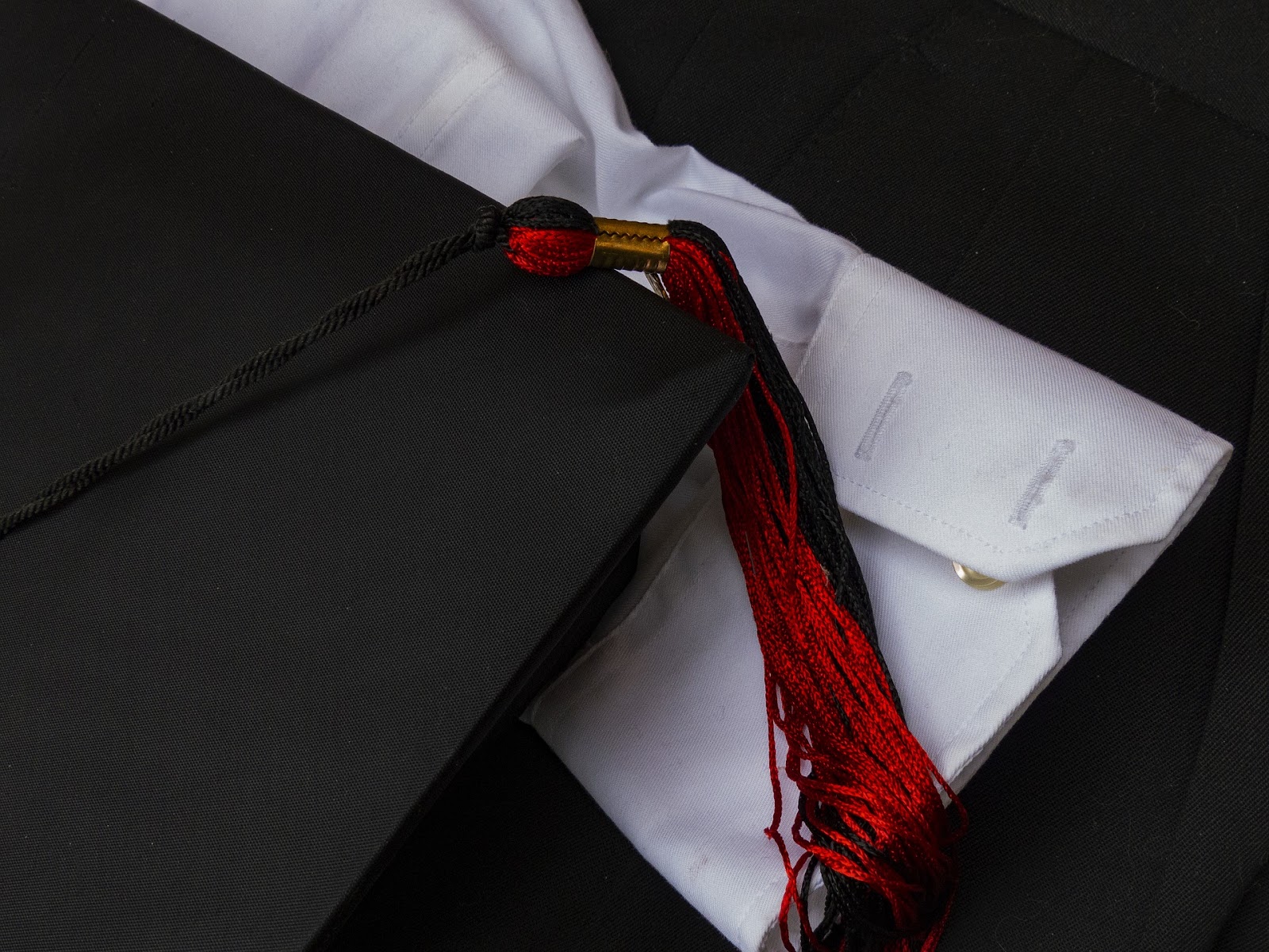 A picture of a graduation cap, tassel, and the cuff of a white dress shirt.