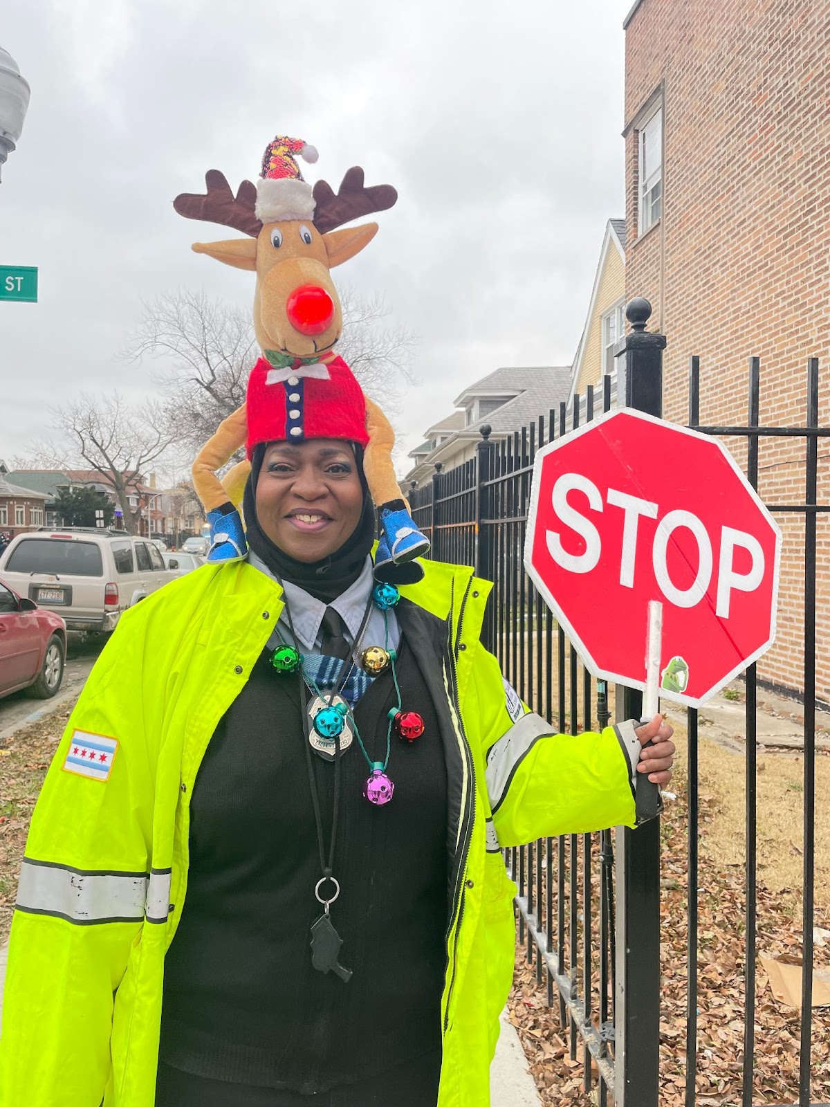 Crossing Gaurd Gail Williams with stop sign and wearing a reindeer decrotive hat