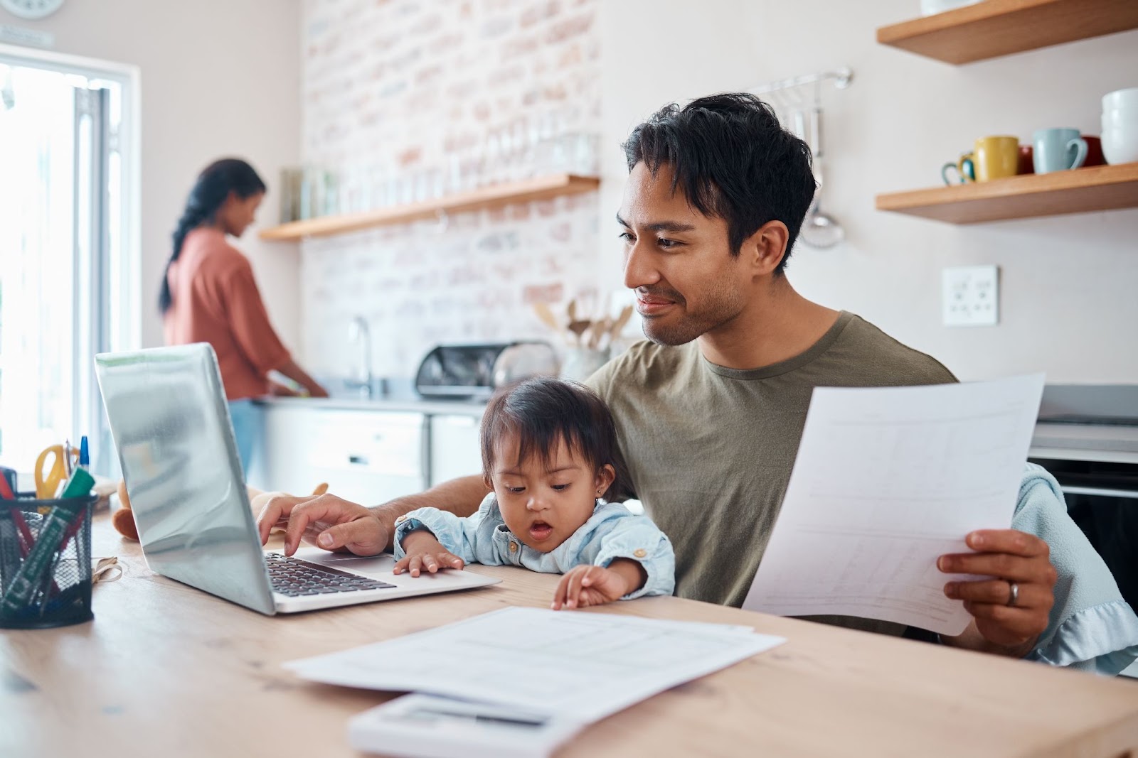 man with baby on lap paying bills 