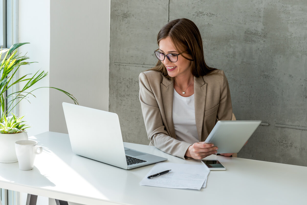 Human resource management system: entrepreneur using a tablet and looking at a laptop