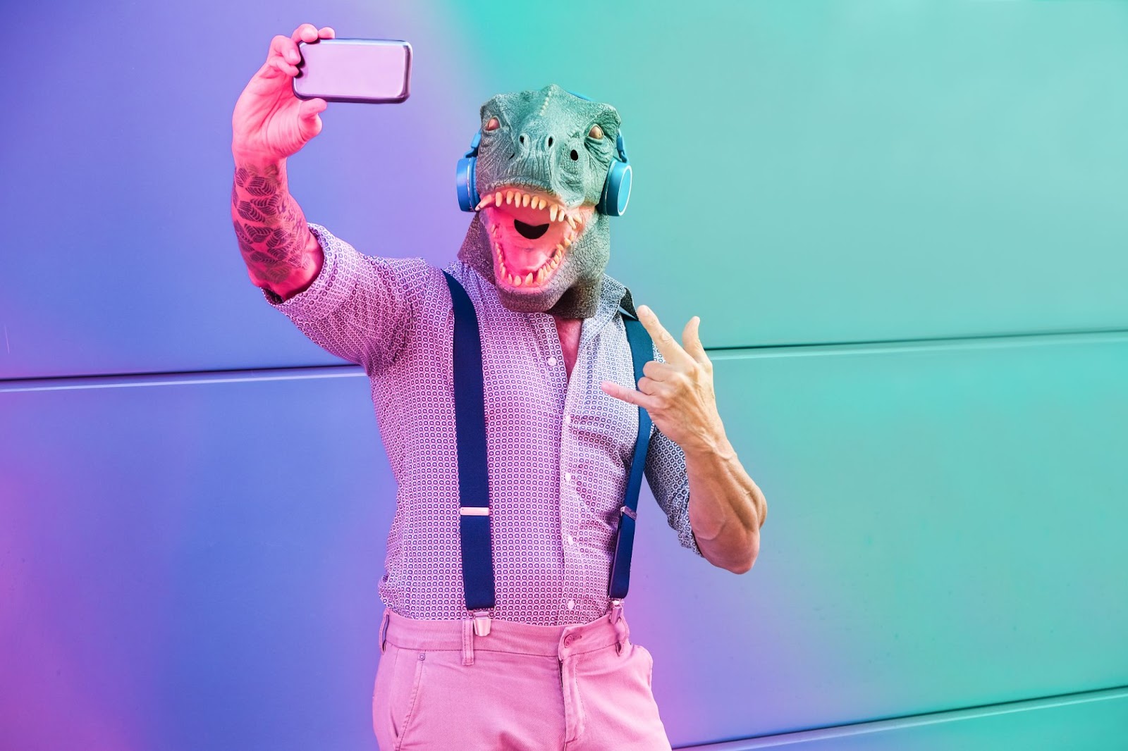 A man in a dinosaur mask taking a selfie.