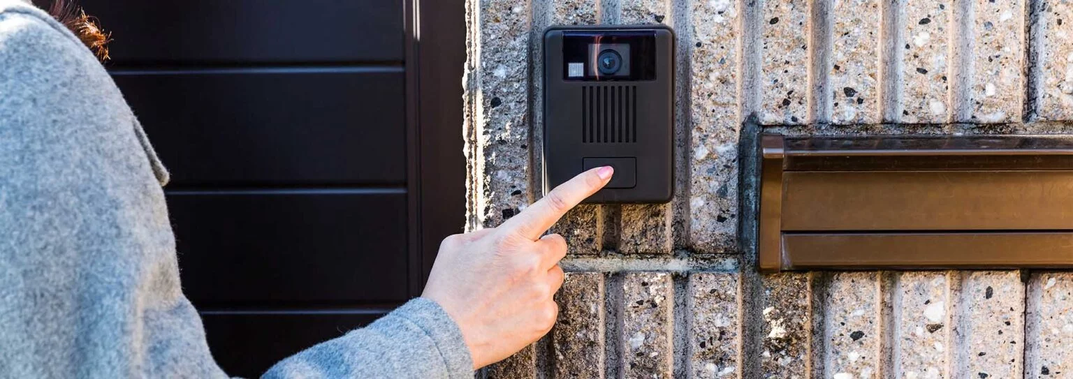 A man at the video dorbell pushing buttons at the door entrance. 