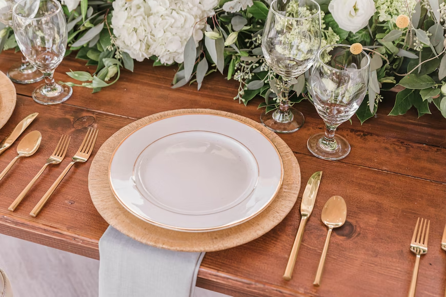 A dining table with gold utensils and glasses