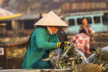 Người phụ nữ Việt Nam với chiếc nón lá (sugegasa) đặc trưng, ​​cắt trái khóm ở chợ nổi Cái Răng, đồng bằng sông Cửu Long.  Cần Thơ, Việt Nam