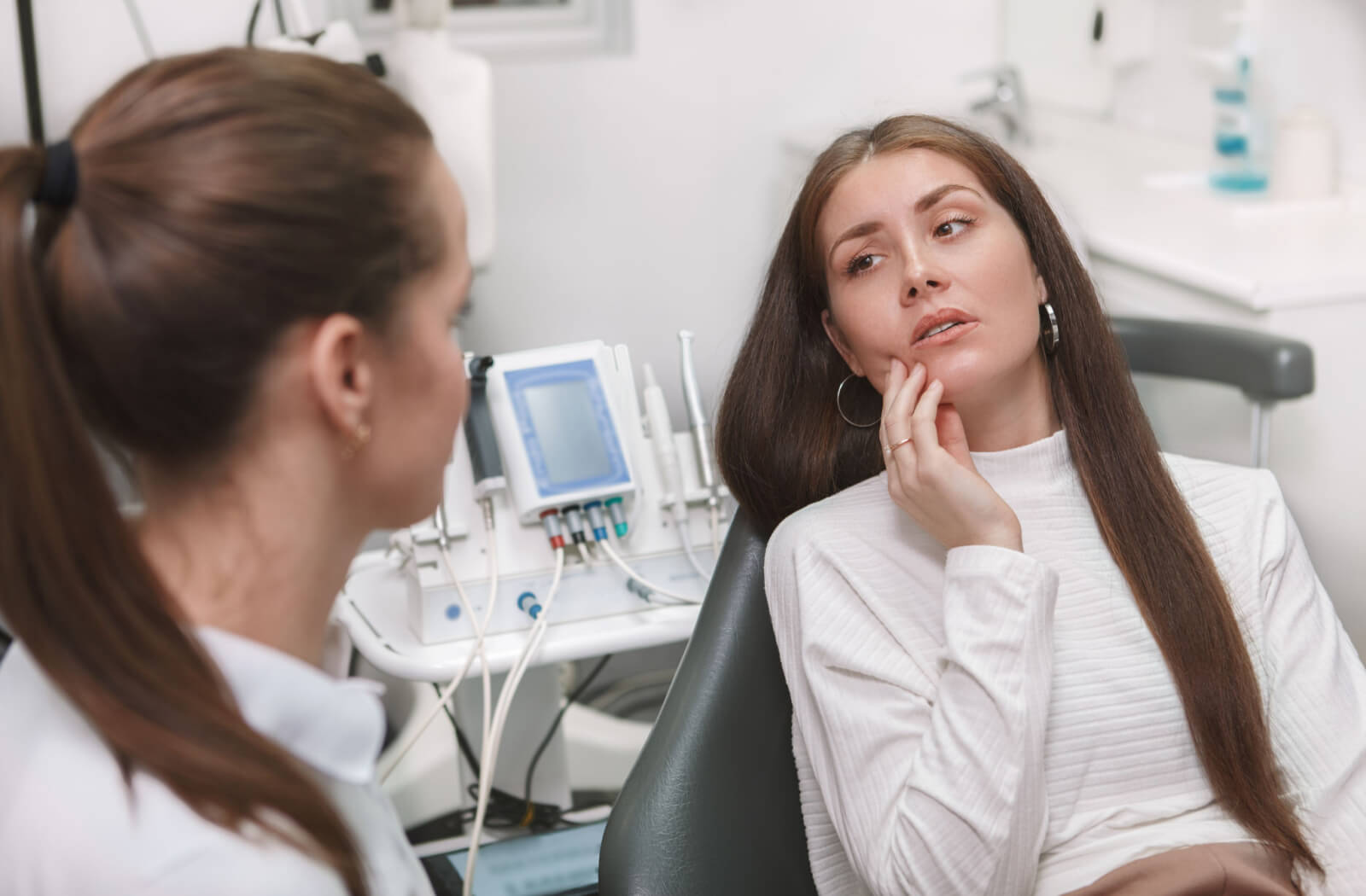 A female patient with painful teeth visits her dentist in a dental emergency.