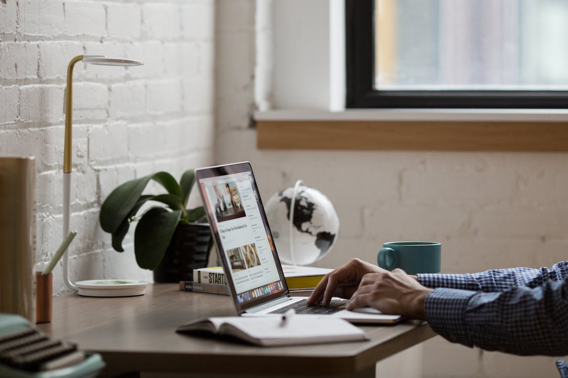 Free Man Sitting in Front of Turned-on Laptop on Brown Wooden Desk Stock Photo