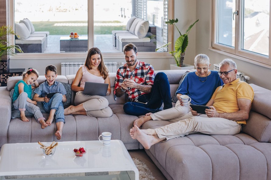 two kids, their parents, and grandparents relaxing on a sectional couch