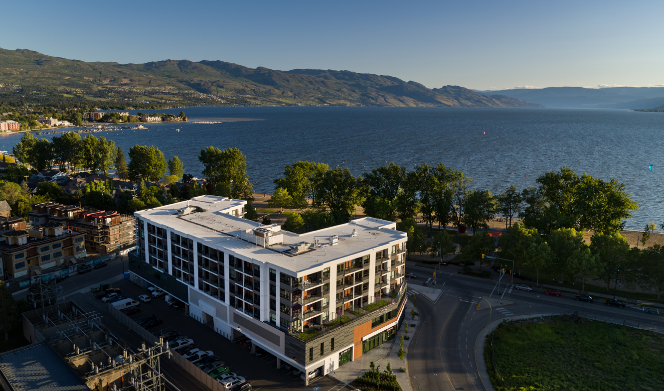 a birds eye view of The Shore Kelowna, showing Okanagan lake and valley mountains in the background over Gyro beach