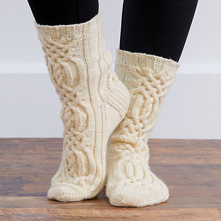 person wearing cream cable knit socks and black leggings