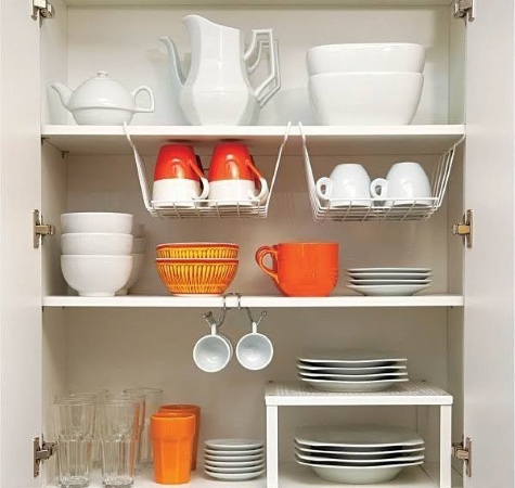 Orange and white dishes and drinkware organized neatly in a cupboard