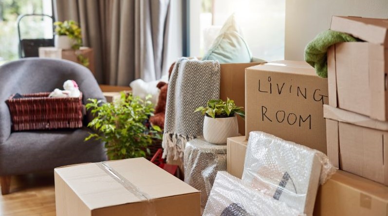 A living room that has just been filled with furniture, moving boxes, and more from a moving truck.