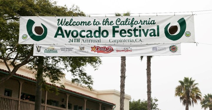 A banner is hanging across a street advertising the annual Avocado Festival in Carpinteria, CA.