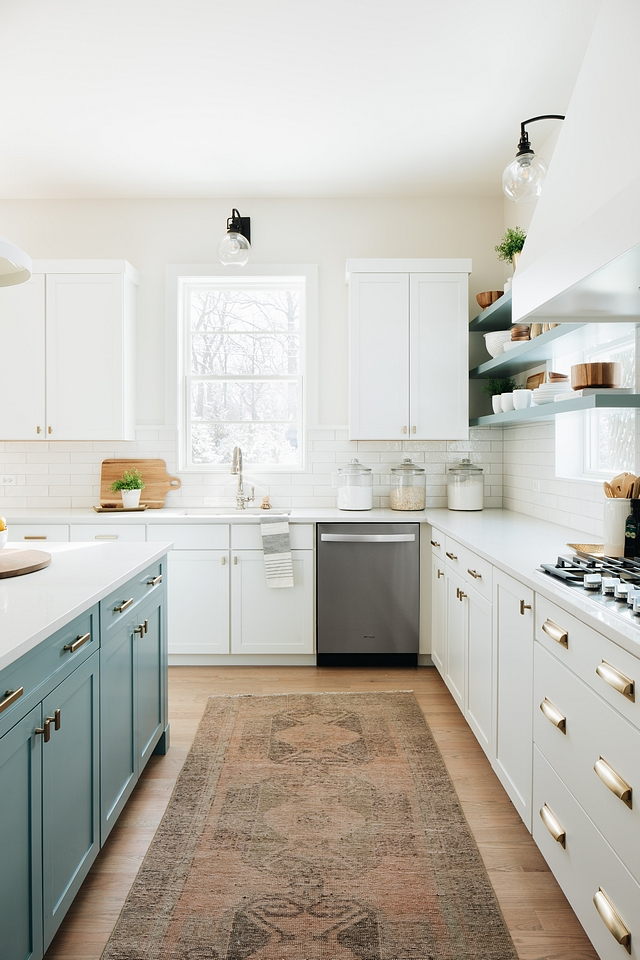 blue cabinets on the kitchen island make it stand out against the white cabinetry in the rest of the kitchen. the two toned look with blue and white cabinets evokes a coastal charm