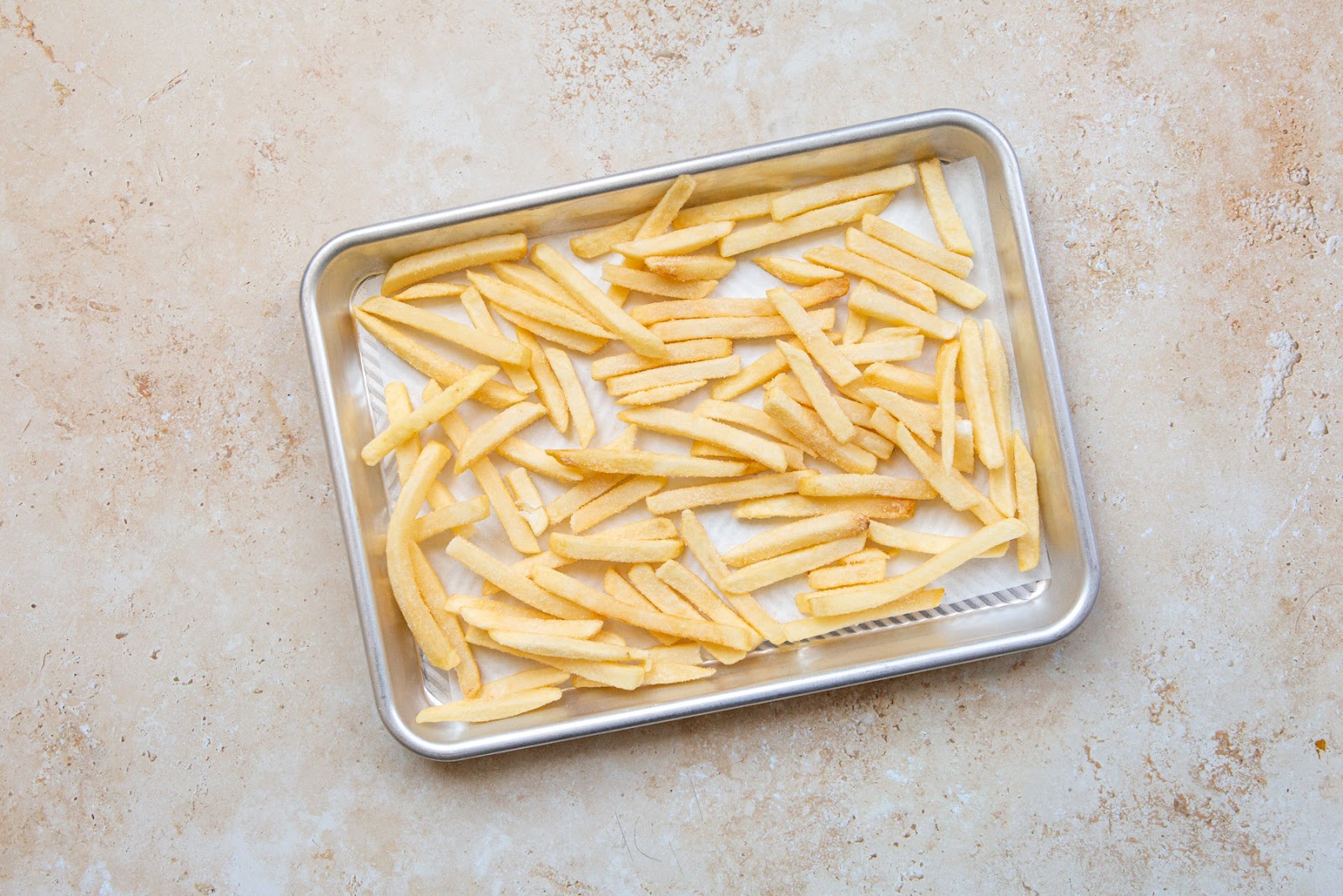 french fries for breakfast poutine placed on a baking sheet