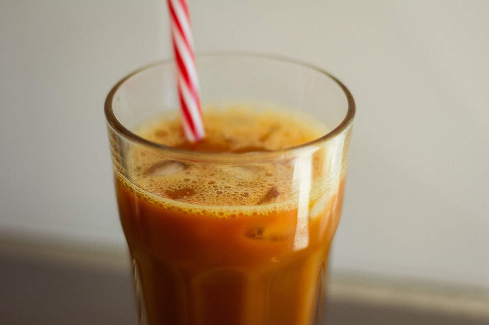 A tall glass of pumpkin milk, with a straw.