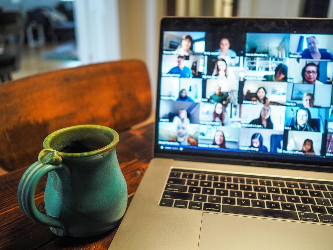 Virtual team meeting with the computer on the counter and a coffee cup nearby