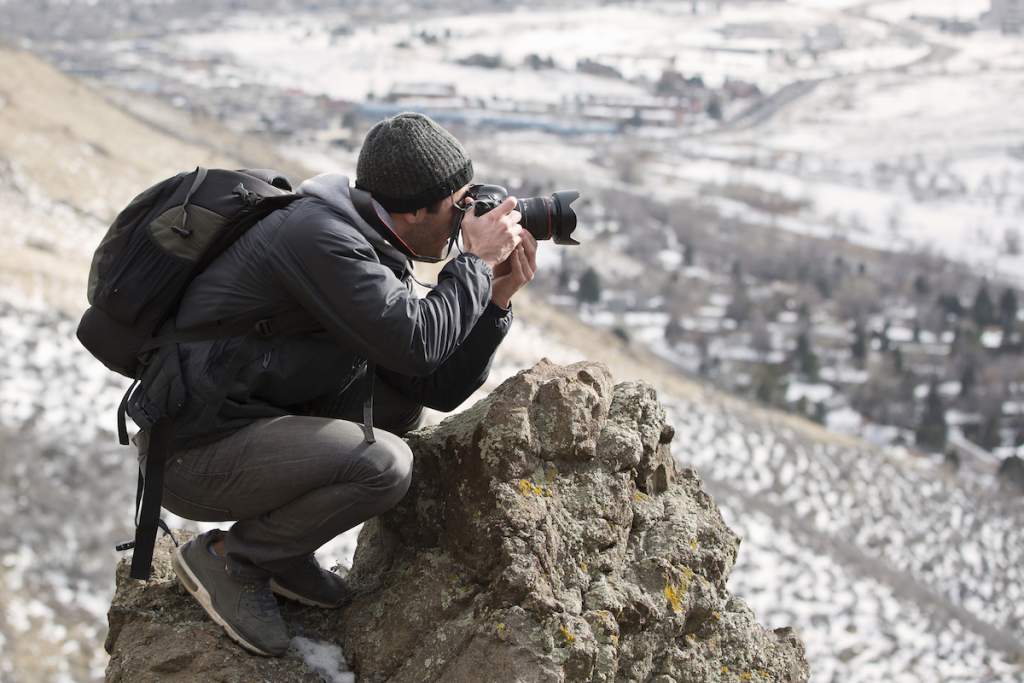 مصور مبتدئ ينظر من خلال عدسة الكاميرا الخاصة به نحو الجبال.
