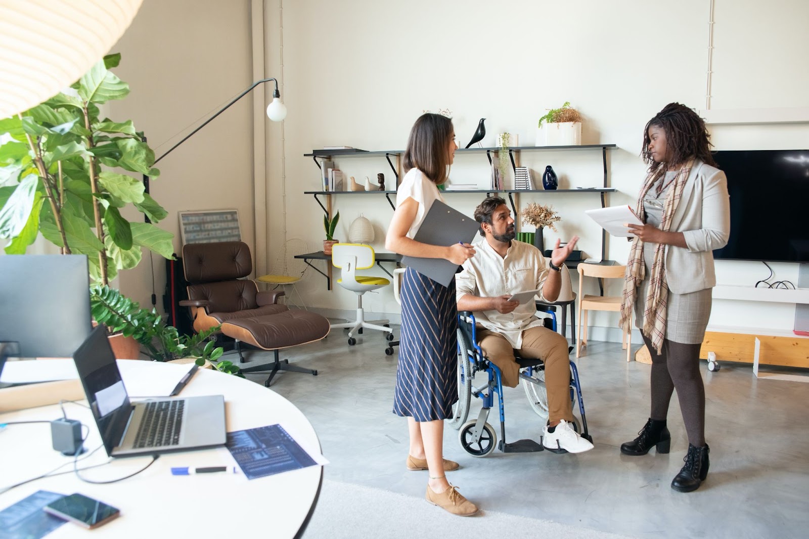 Three colleagues engaged in conversation in a modern and inclusive workspace