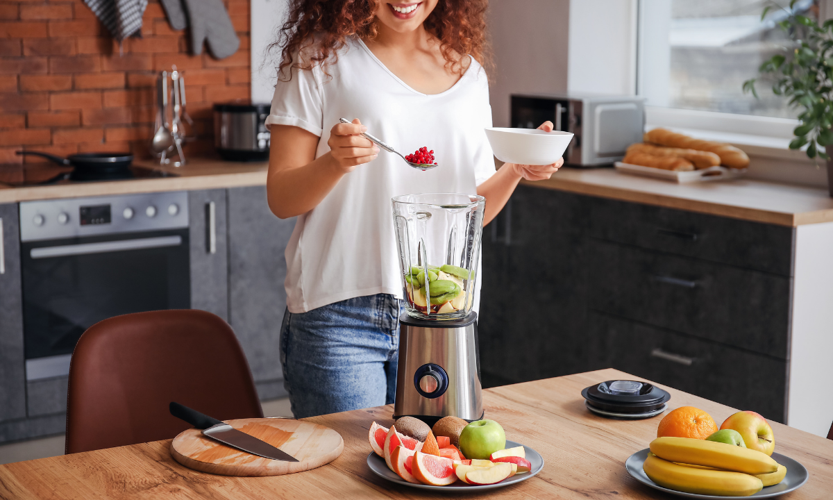 woman putting fruit in a blender, one of  the best vegan kitchen appliances