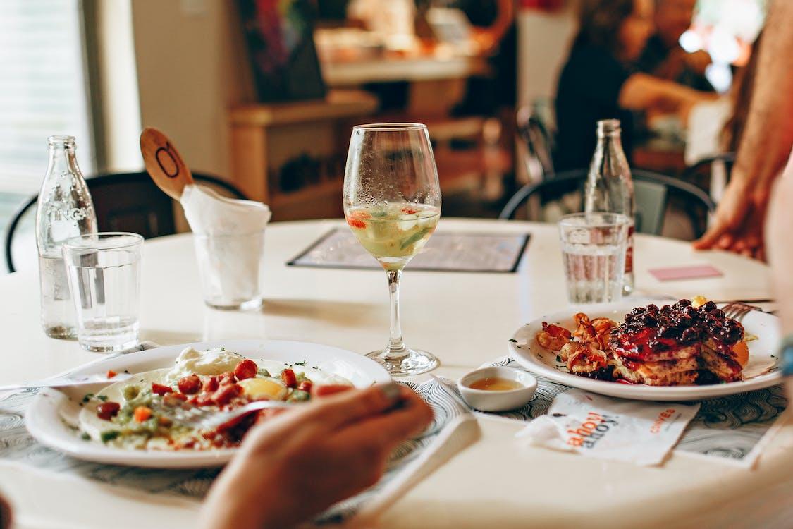 бесплатная Вино в прозрачном стекле возле еды на тарелке на столе Стоковое фото