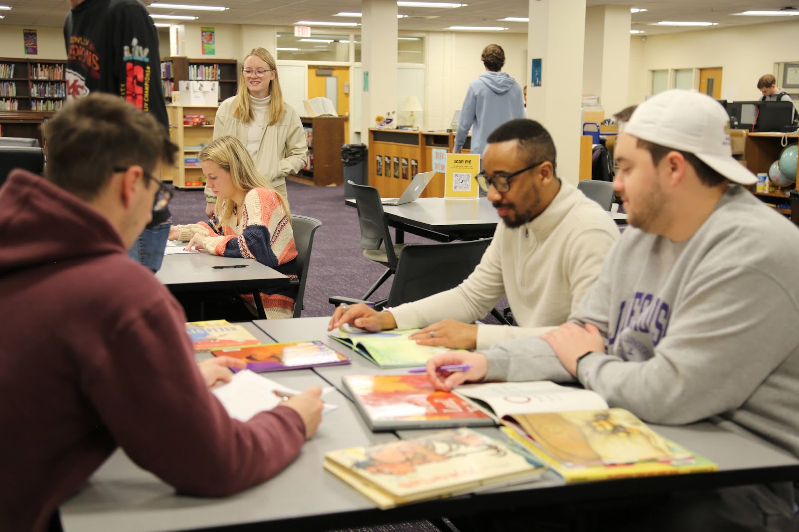 photo of 8 students in the ETMC crowded around tables covered in children's books