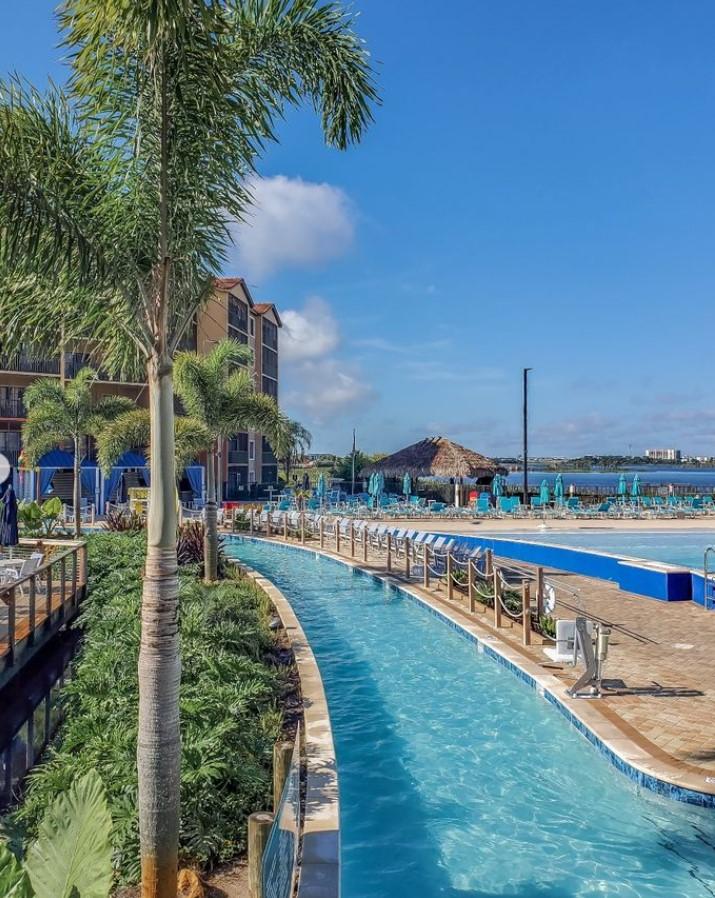 A pool with palm trees and a building

Description automatically generated
