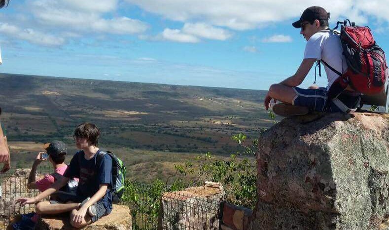 A imagem mostra jovens em uma paisagem de montanhas.