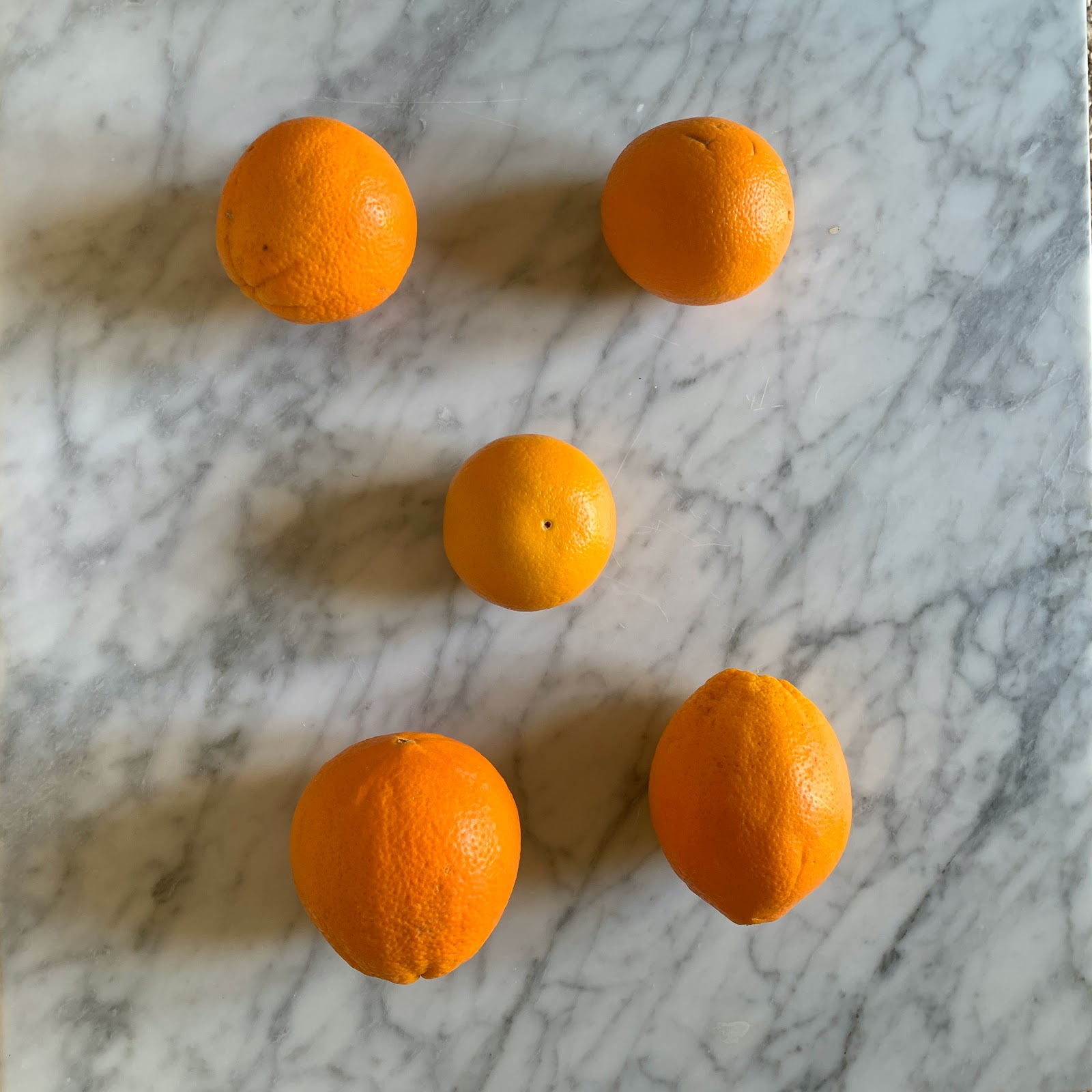Oranges arranged like dots on a die or domino. 2 then 1 then 2 more.