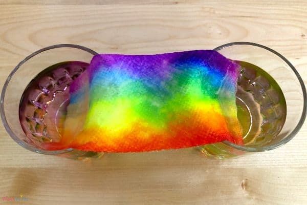 a rainbow paper towel between two glasses of water