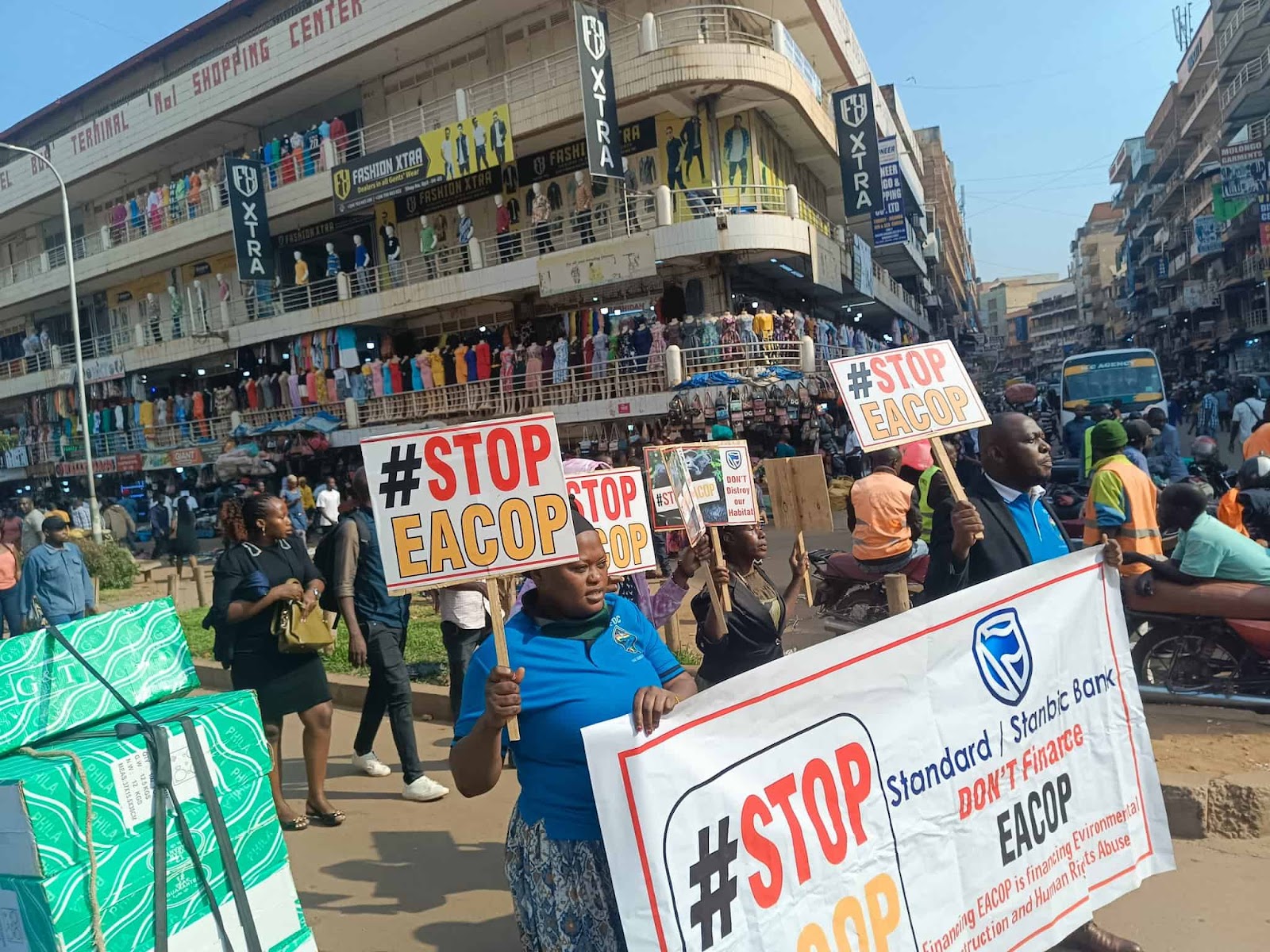 A rally through a busy city with lots of Stop EACOP banners and signs