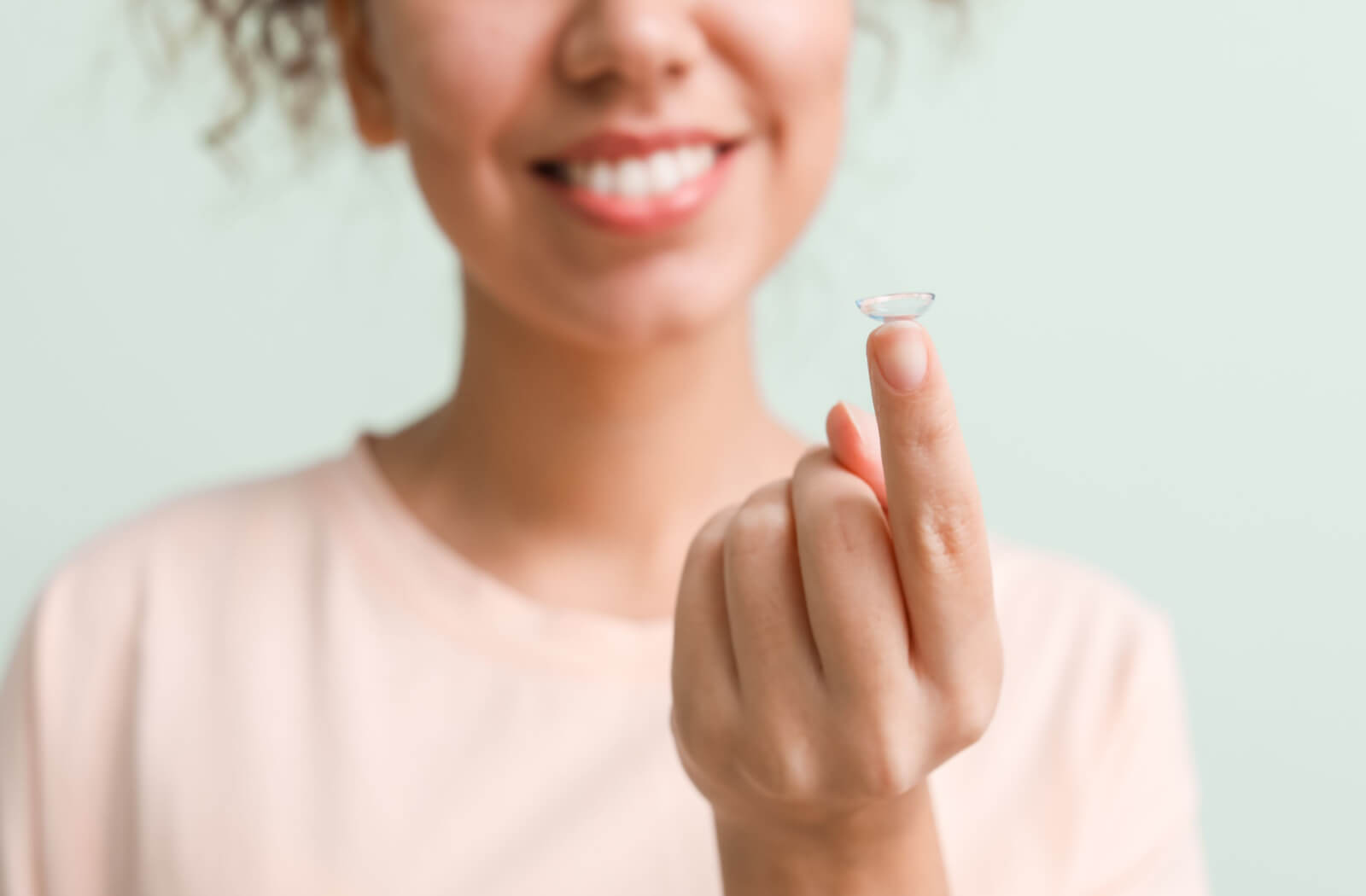 a woman holds a contact lens on her finger that fits perfectly because she had a contact lens fitting