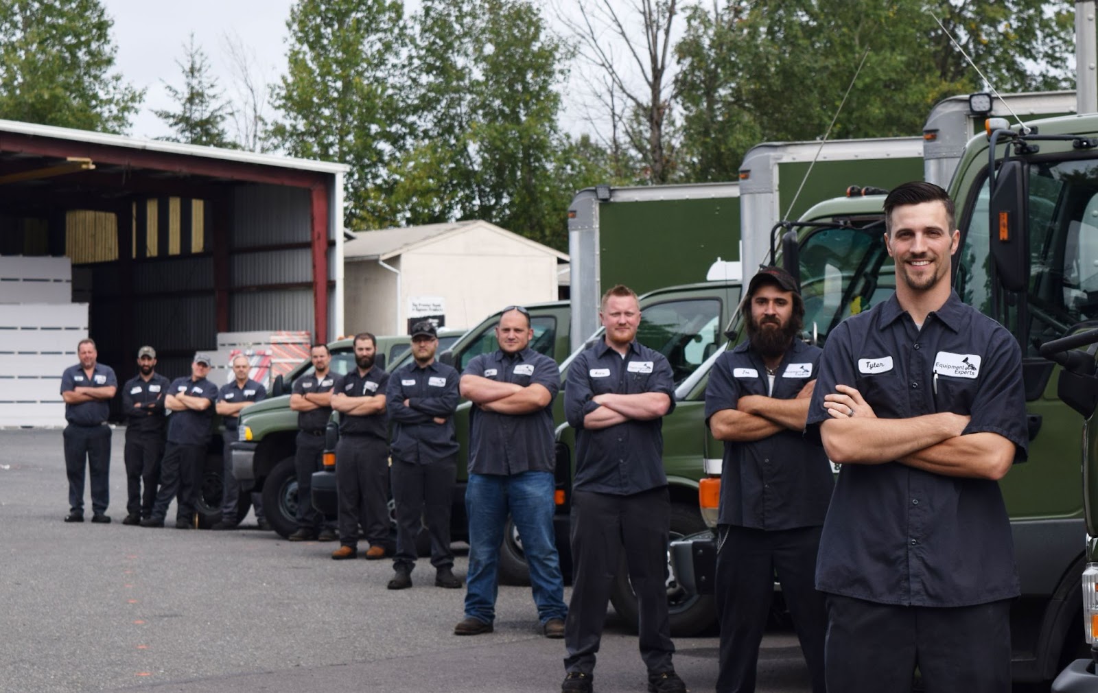 11 employees standing in a diagonal line against individual trucks