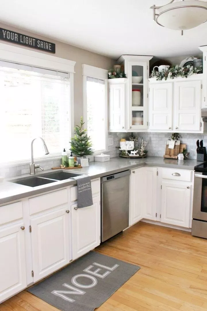 traditional white kitchen with simple christmas decor including pine garland on top of the white cabinets