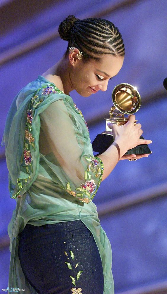 Alicia Keys wearing cornrows for styling natural short hair and holding an award