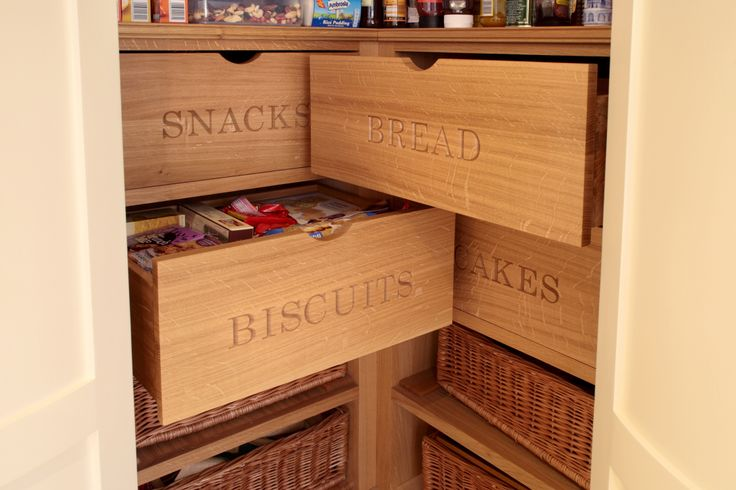 Pull-out wooden drawers in a pantry with category labels carved into them.