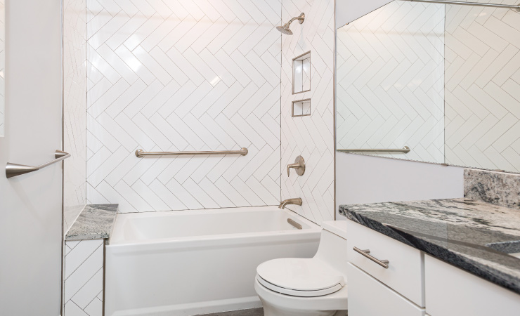 A newly redesigned shower with white subway tile in a herringbone pattern