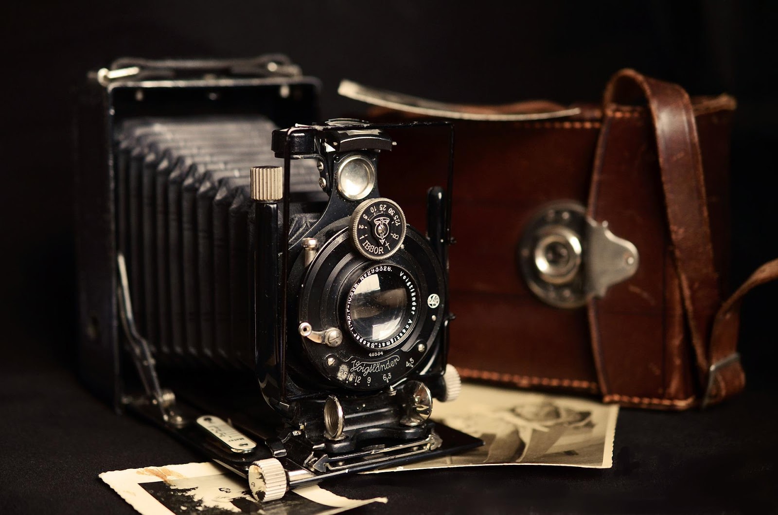 A vintage camera and camera bag sit on a table with two black and white polaroids. An example of how to use images for SEO optimization.