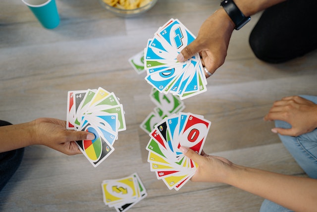 three people holding fanned out uno cards
