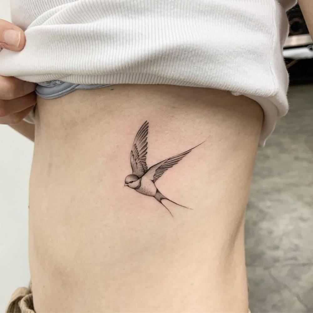 Micro-realistic swallow tattoo on the rib.