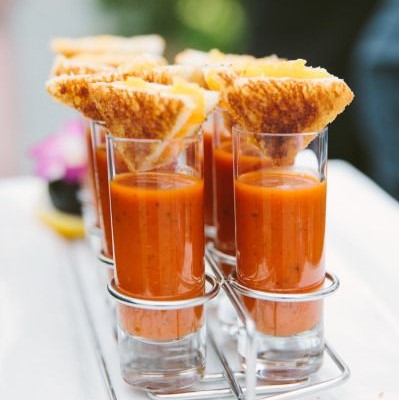 small cups of tomato soups and a small piece of grilled cheese