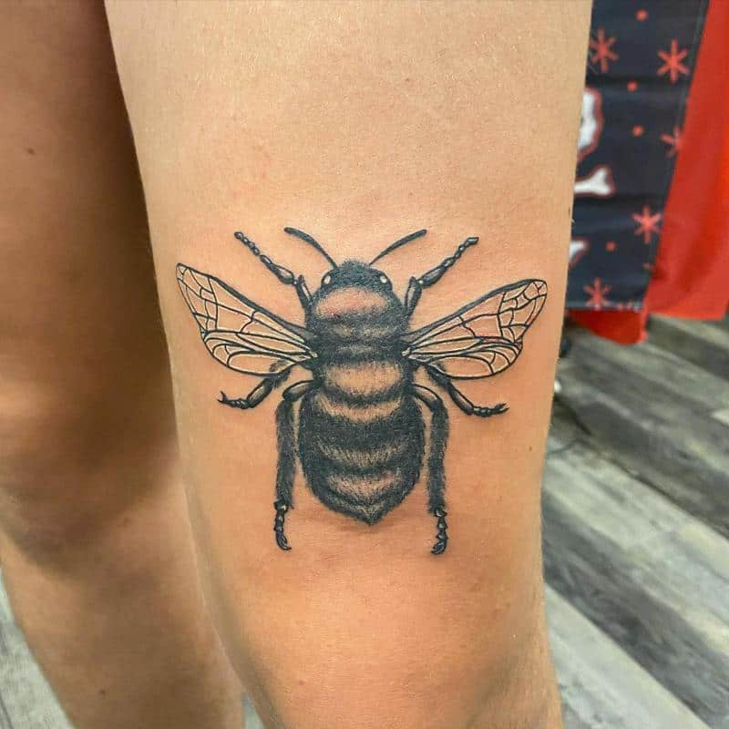 Full picture  of a guy rocking the bee tat design on his knee