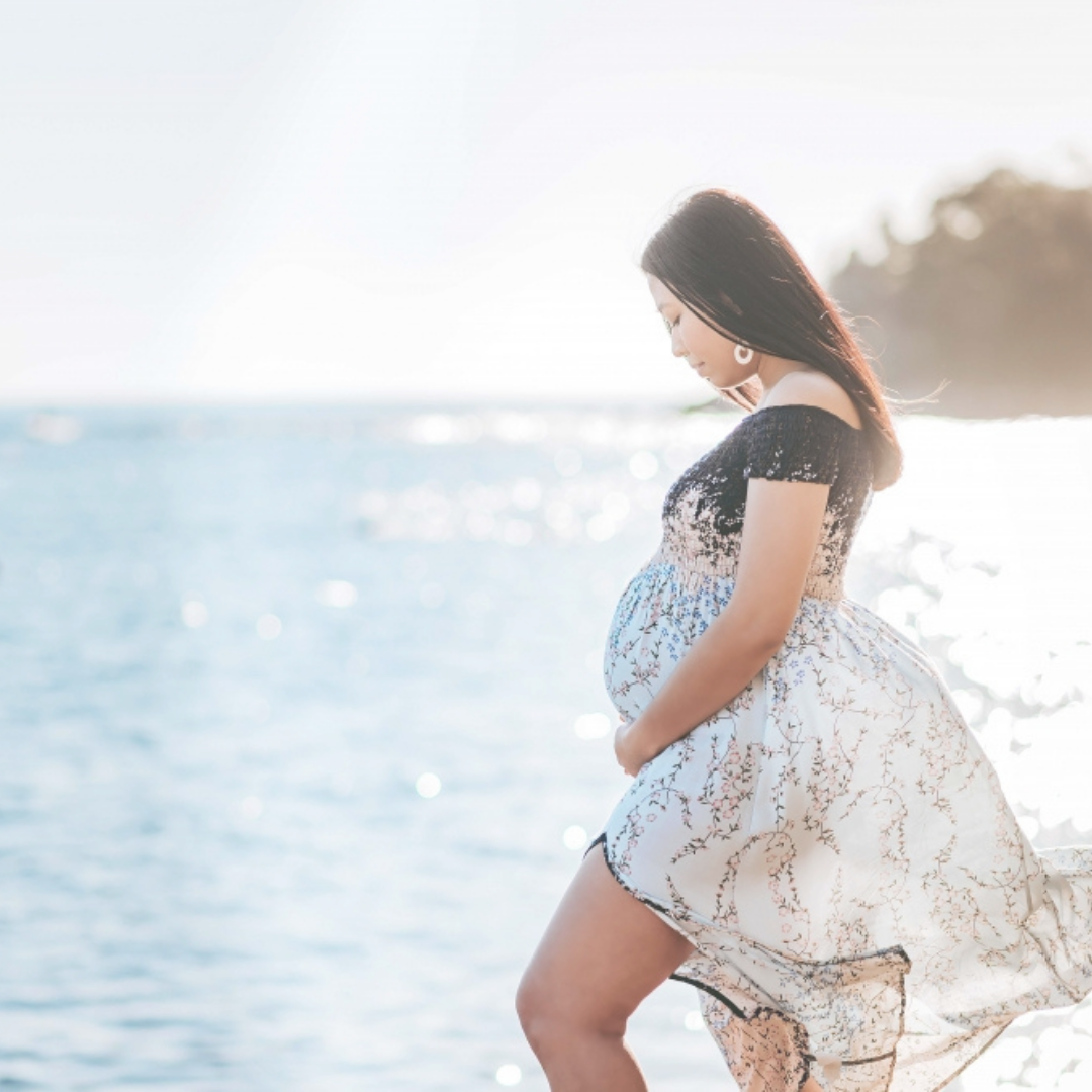 A pregnant woman holding her belly in the beach