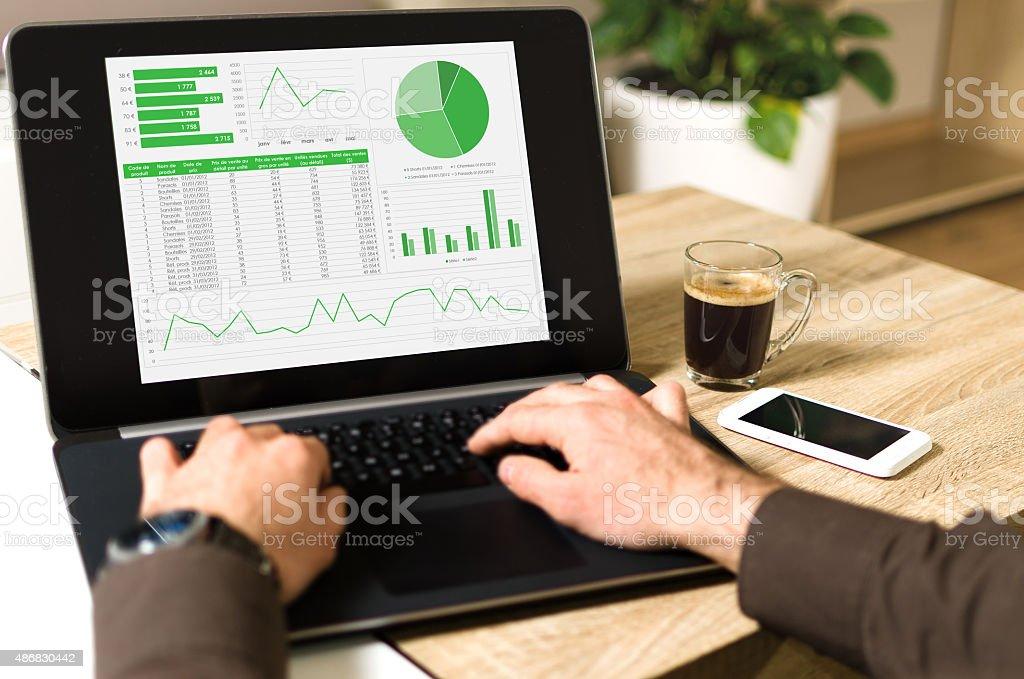 Analyzing data on a laptop computer (pov) Point of view (POV) picture of a Businessman analysing financial data on laptop computer, and beside there is a coffee and a white smartphone. Personal Perspective Stock Photo