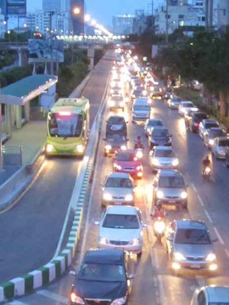Picture of an urban roadway at dusk showing heavy traffic congestion in three lanes, and a city bus travelling along dedicated enclosed lane with no impedances.